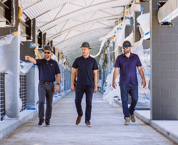 Three businessmen in hard hats tour a Karlin real estate project that is under construction