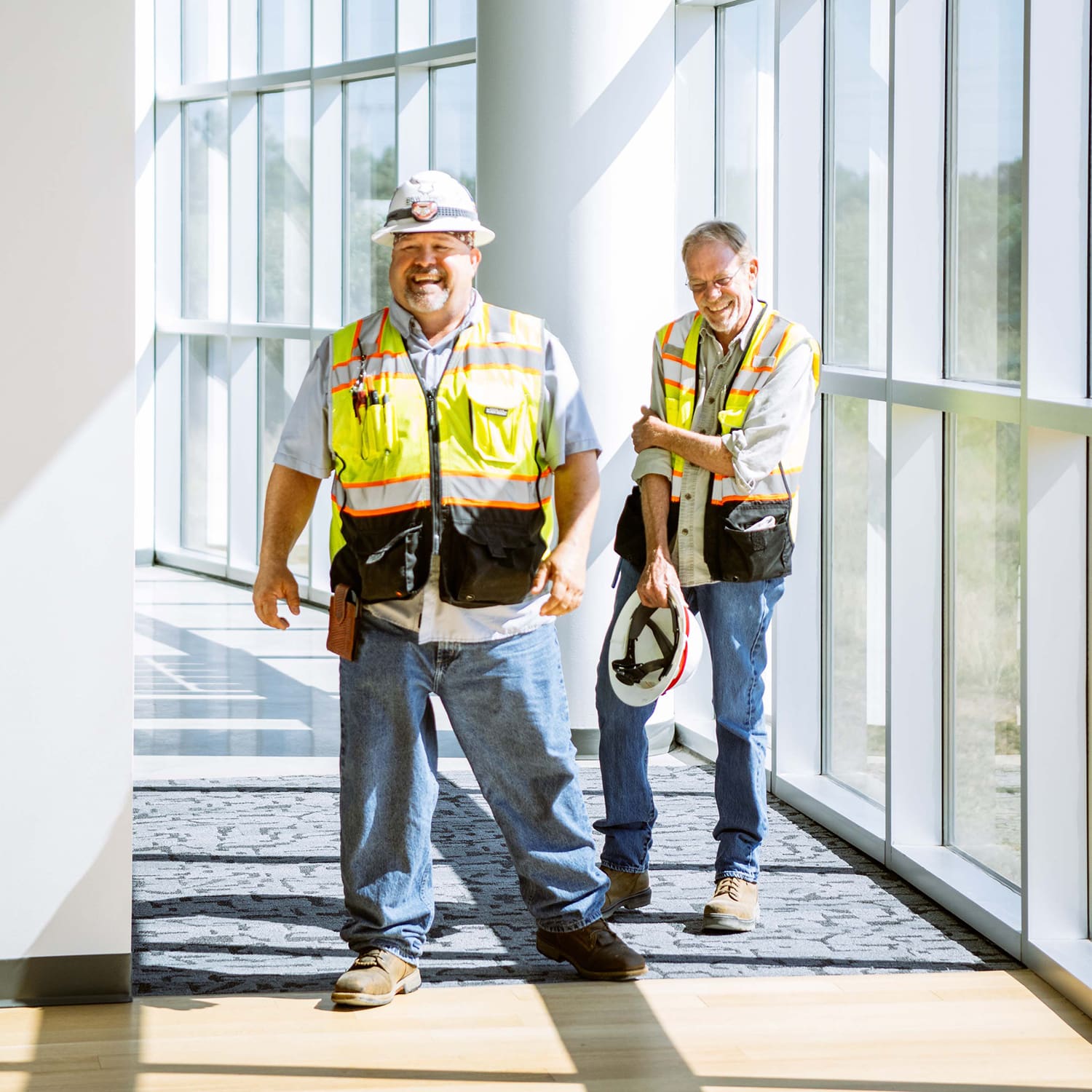 Two construction workers in an office hallway