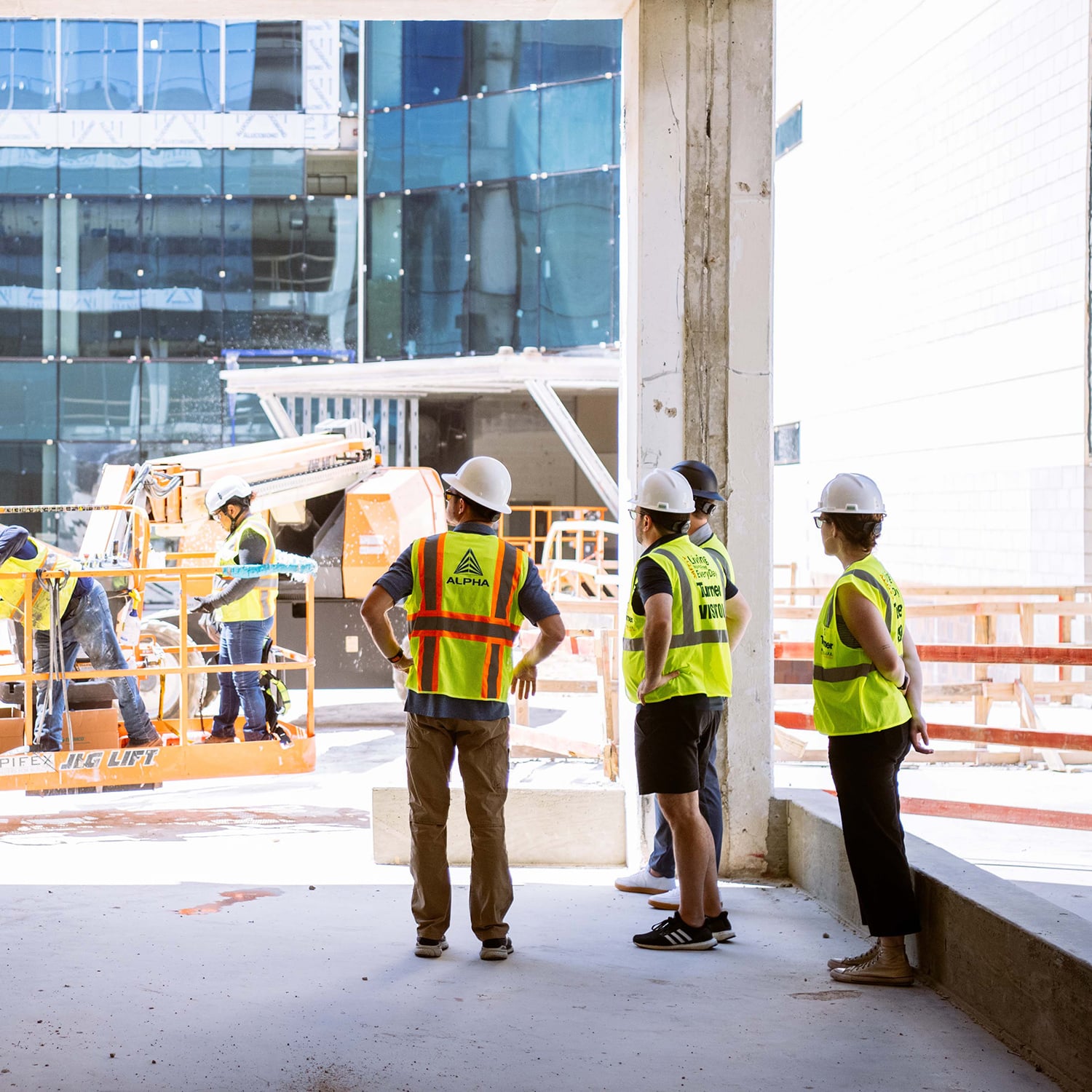 Four professionals in hard hats and vests tour a Karlin real estate project that is under construction