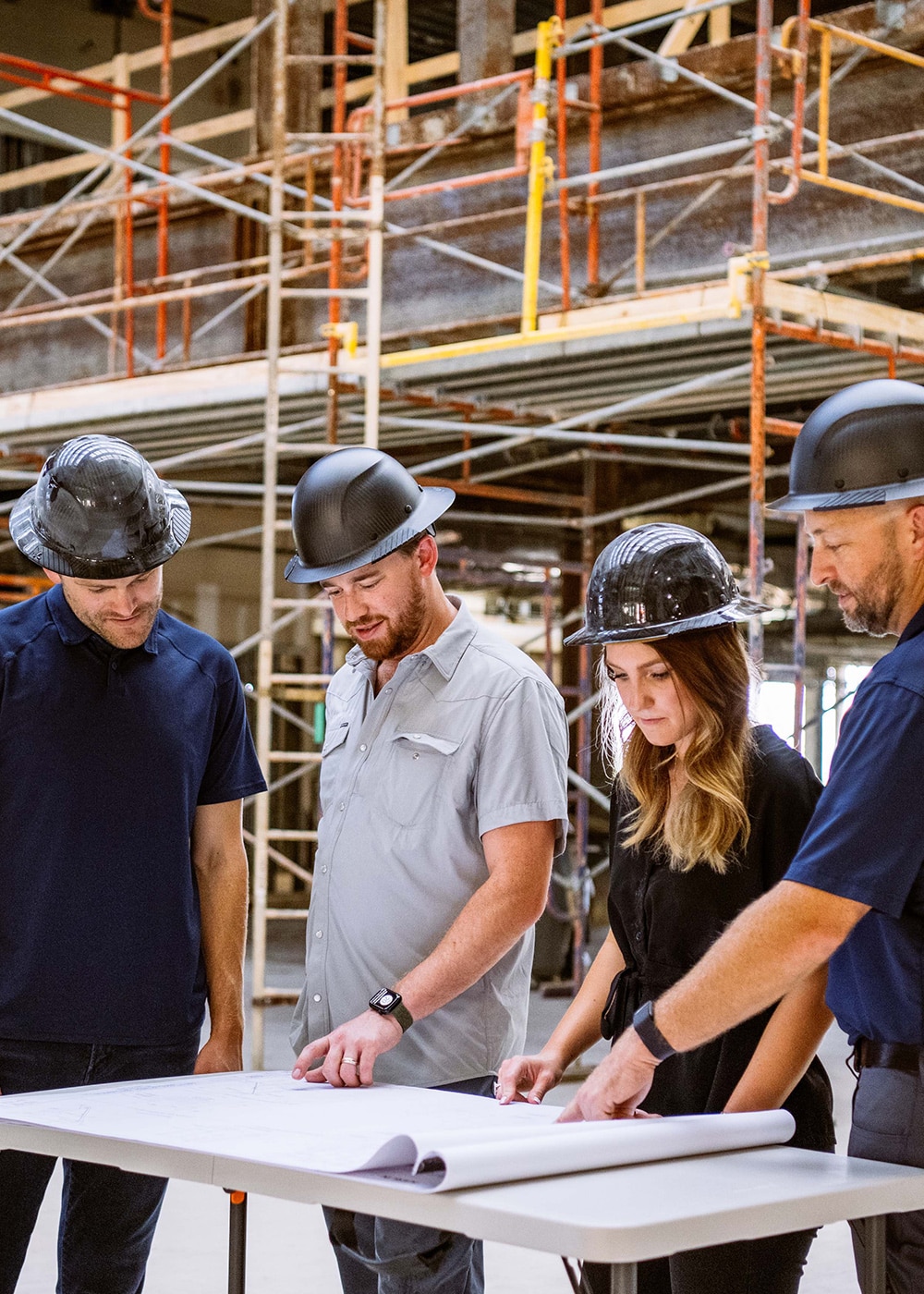 Four professionals in hard hats view plans for a Karlin real estate project that is under construction