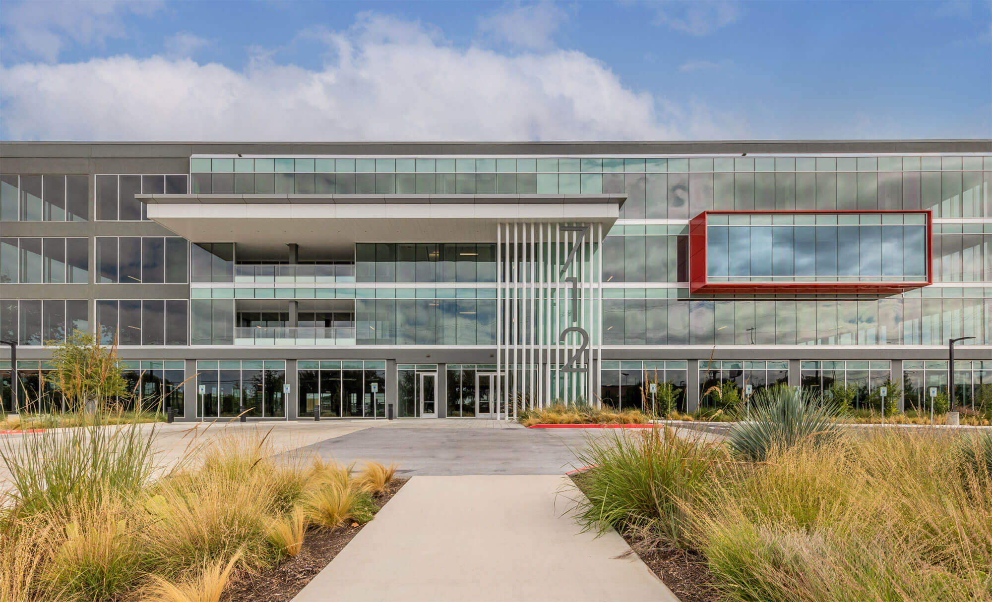 Front entrance of a modern office building with large windows and a red accent