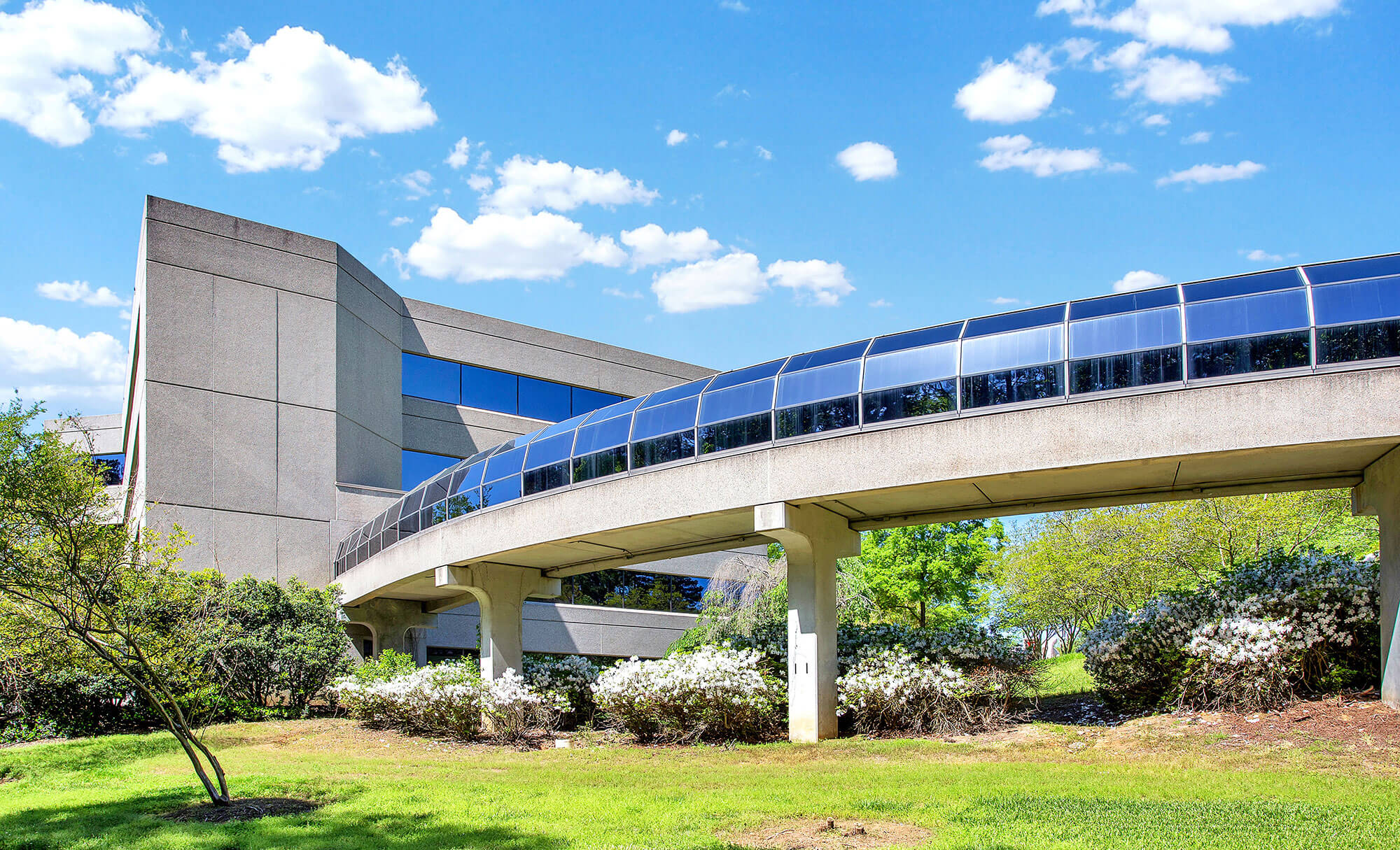 Modern office architecture at Parmer RTP featuring a curved skywalk and green surroundings