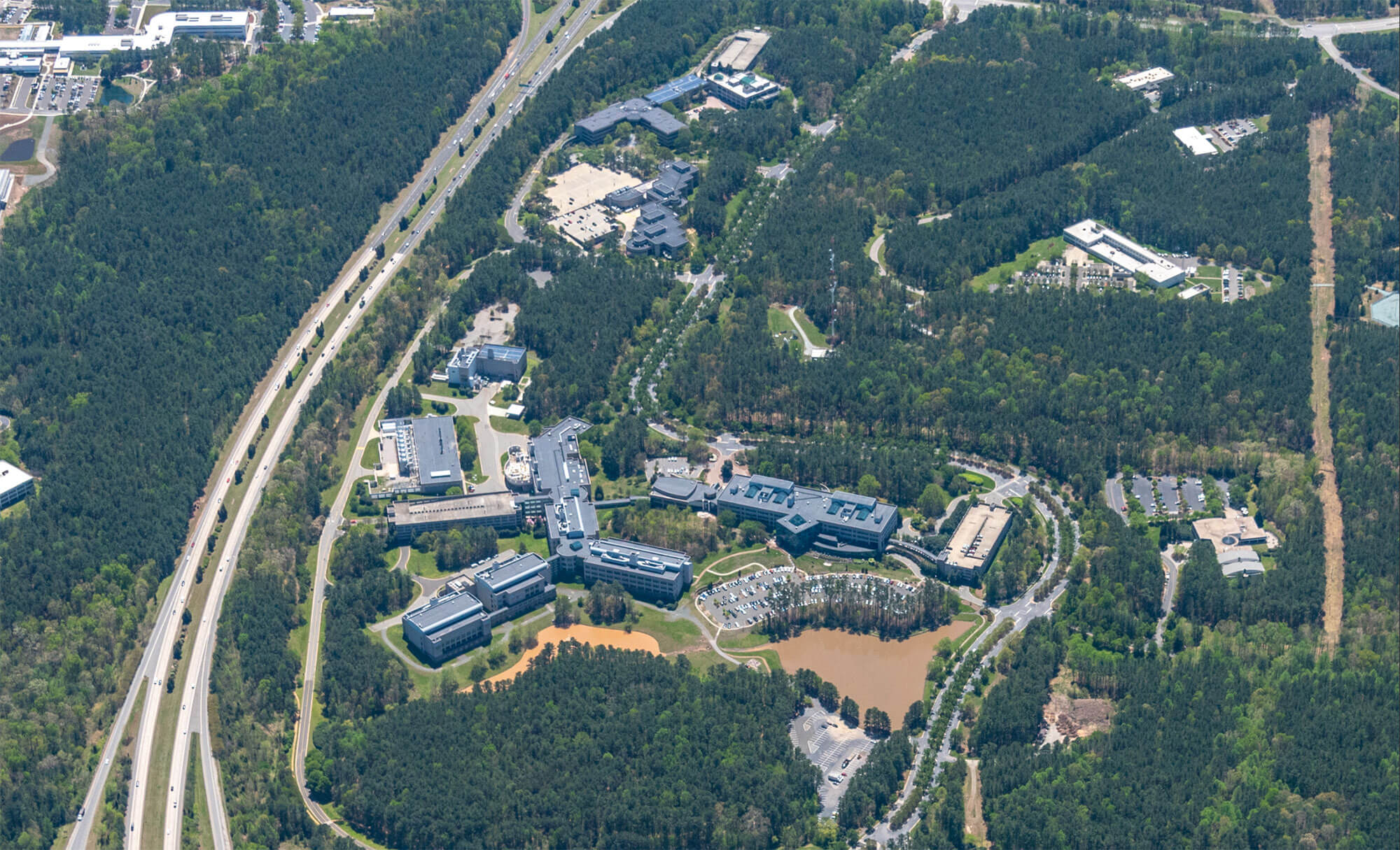 Aerial view of Parmer RTP campus showing multiple buildings surrounded by dense forest