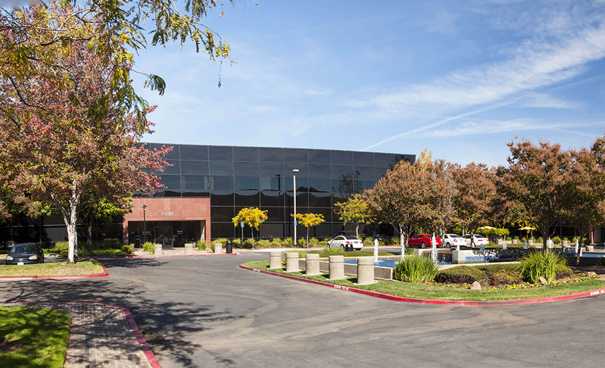 Wide-angle shot of Parmer West office with landscaped driveway and parking